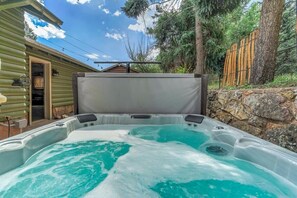 A hot tub with a stone wall and wooden fence in the background.