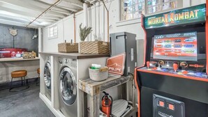 A laundry area with washers and dryers, a Midway arcade machine, and a UPSlope Brewing Company sign. - 4BR Mountain Getaway w/Hot Tub Firepit & Game Room (Cascade-Chipita Park)