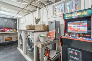 Een wasruimte met wasmachines en drogers, een Midway arcadekast, en een bord van UPSlope Brewing Company.