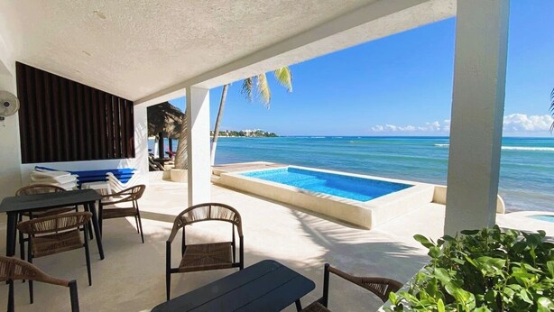 A poolside area with a view of the ocean, a table with chairs, and a covered seating area. - Beach-Level Escape Featuring a New Private Plunge Pool and Ocean Views! (Akumal)