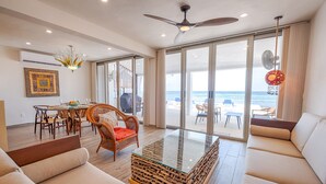 A spacious living area with a glass coffee table, wicker chairs, and a sofa. - Beach-Level Escape Featuring a New Private Plunge Pool and Ocean Views! (Akumal)