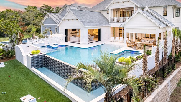 A large house with a swimming pool, multiple decks, and outdoor furniture.