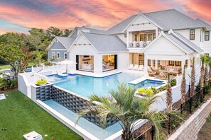 Una casa grande con piscina, varias terrazas y mobiliario de exterior.