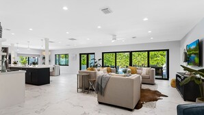 A spacious living area with a marble floor, a large sofa, a coffee table, and a television.