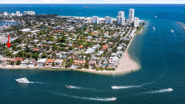An aerial view of a coastal city with dense residential areas, a beach, and a marina with boats.