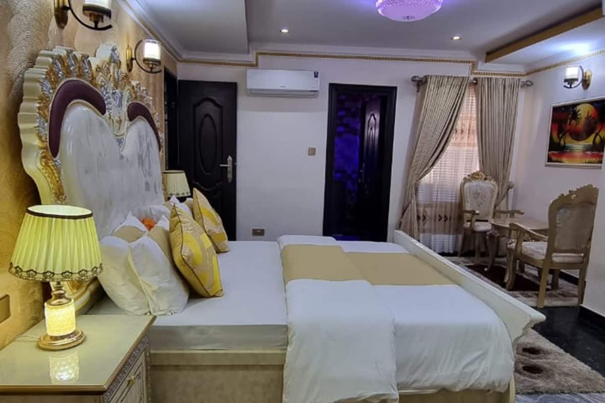 Um quarto espaçoso com uma cama grande, um espaço para sentar e uma cabeceira decorativa.