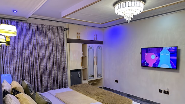 A modern bedroom with a bed, a TV, and a wardrobe. - Tobby Royal Suites (Lagos)