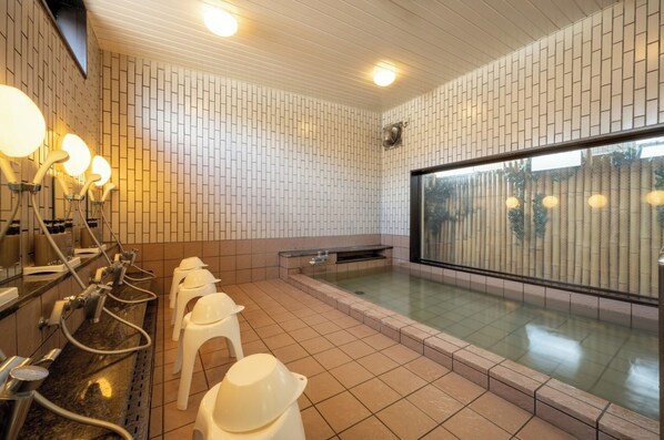 Relax in a spacious bathroom with a large bathtub, glass enclosure, and seating area.