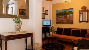 Un soggiorno con un tavolo in legno, un divano, una TV e un quadro appeso al muro.