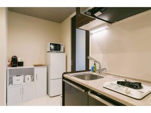 A compact kitchen with a microwave, sink, and stove.