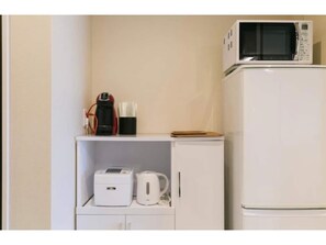 A kitchenette with a microwave, coffee maker, and a small refrigerator.