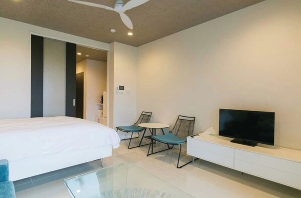 A modern hotel room with a bed, a TV, a small table, and two chairs.