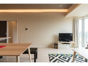 Una sala moderna con televisor de pantalla plana, una mesa de comedor y una alfombra estampada.