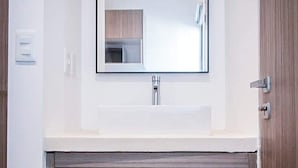 Ein Badezimmer mit einem weißen Waschbecken, einem Spiegel und einer Holzkosmetikkommode mit Schubladen.