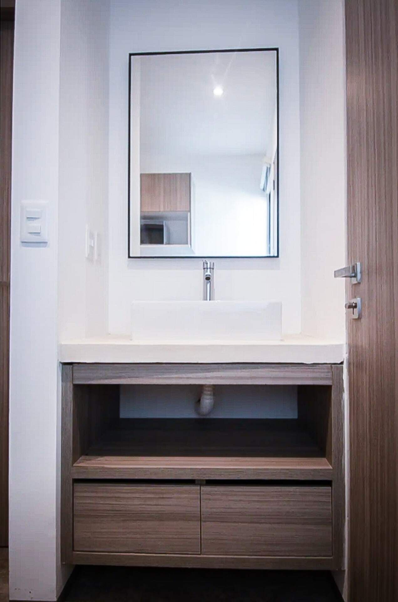 A bathroom with a white sink, a mirror, and a wooden vanity with drawers.