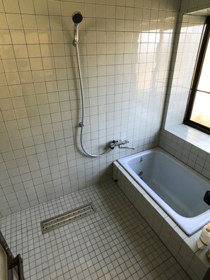 Une salle de bain avec une baignoire, une douche et une fenêtre.