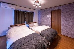 Une chambre d’hôtel avec deux lits, une porte en bois et un papier peint à motifs.