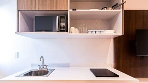A modern kitchen with a built-in microwave, a stainless steel sink, and a black induction cooktop. - Trendy Studio - Pool, Rooftop & Near Beach (Playa del Carmen)