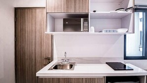A compact kitchen with a built-in microwave, a sink, and a countertop. - Stylish Condo - Pool + Rooftop - Walk to 5th Ave (Playa del Carmen)