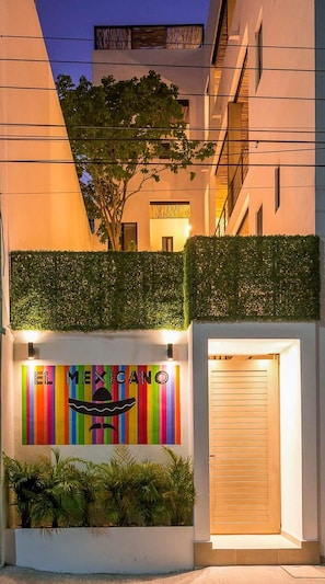 A building with a colorful mural reading "EL MEXICO" and a closed wooden door.