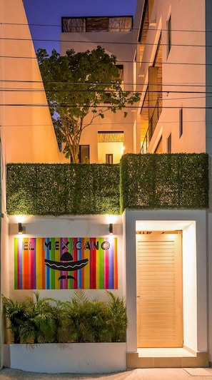 A building facade with a colorful mural reading "EL MEXICO" and a closed wooden shutter door.