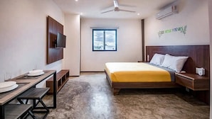 Quarto com cama, escrivaninha, televisão e janela.