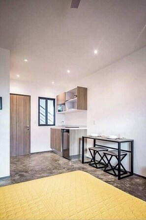 Cozy living space with a kitchen area, dining table, and a large bed.