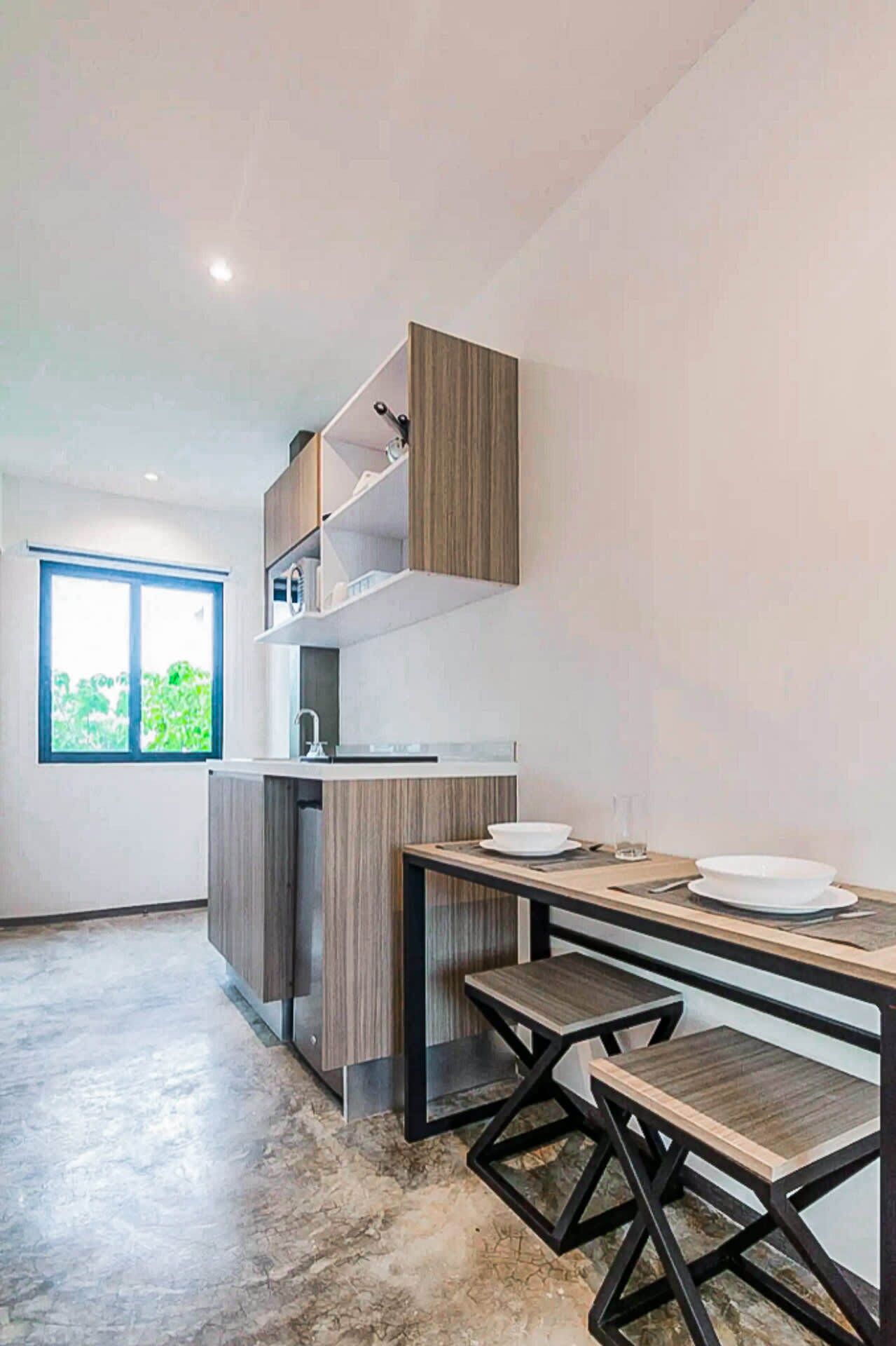A modern kitchen with built-in cabinets, a countertop, and a dining area with a table and benches.