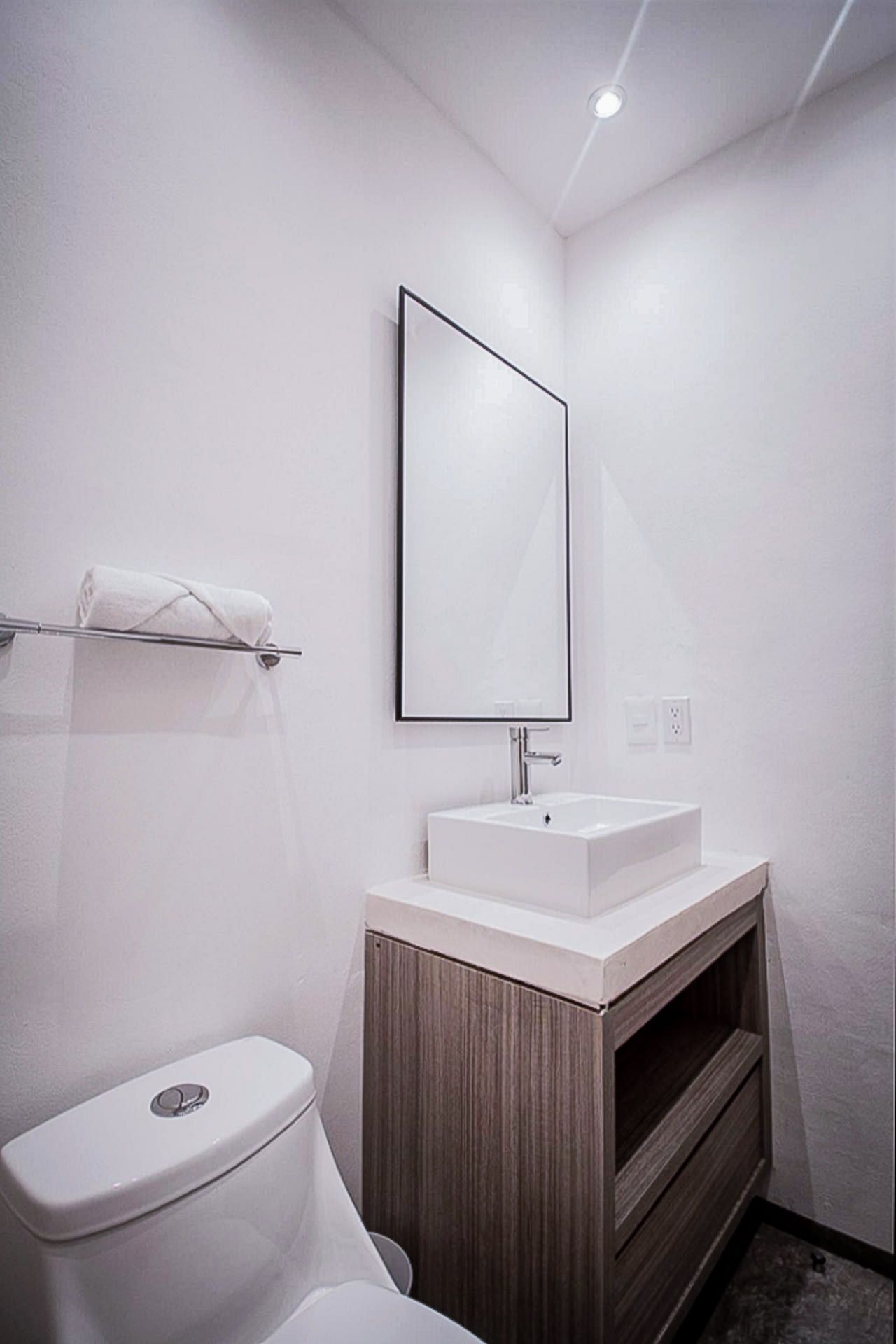 Ein modernes Badezimmer mit Toilette, Waschbecken mit Spiegel und Handtuchhalter.