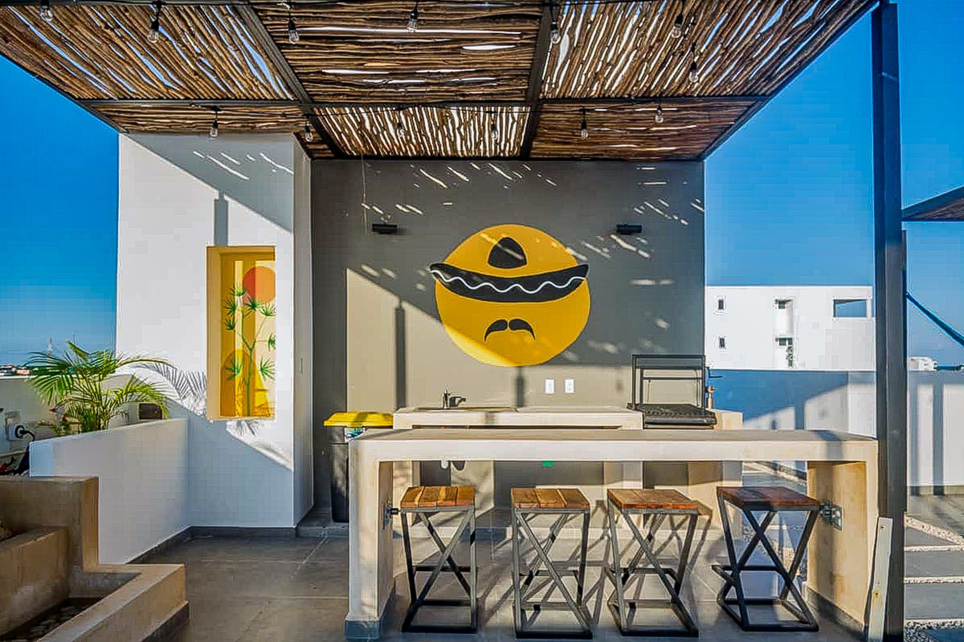 A modern outdoor kitchen area with a unique wall art piece, a bar counter, and stools.