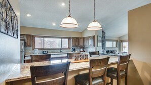 Una cocina amplia con una isla grande, sillas de madera e iluminación colgante.