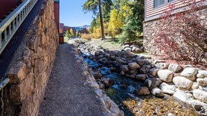 Un estrecho sendero de piedra junto a un edificio con pared de piedra y terraza de madera.