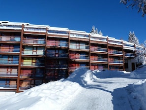 Un hôtel à plusieurs étages, doté de balcons et entouré de neige.