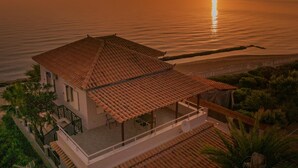 A coastal property with a tiled roof, a balcony, and a view of the sea at sunset. - Villa Elizabeth   Seafront Classic Villa! (Zakynthos)