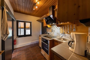 A compact kitchen with wooden cabinets, a built-in oven, a microwave, and a coffee maker. - House in the forest with fenced garden (Altenkirchen)