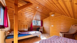 Ein gemütliches Blockhaus mit zwei Holzbett, einem Sessel und einem kleinen Tisch.