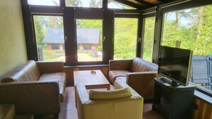 Ein Wohnzimmer mit Ledersofas, einem Couchtisch und einem Fernseher auf einem Standfuß.