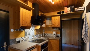 Eine kleine Küche mit Holzschränken, einer gefliesten Rückwand und einem Einbauofen.