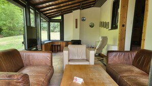 Ein überdachter Außenbereich mit Ledersofas, einem Holztisch und einem weißen Stuhl.