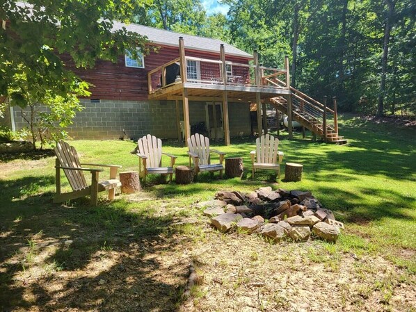 Une terrasse en bois avec des fauteuils Adirondack, un foyer et un bâtiment au style rustique.