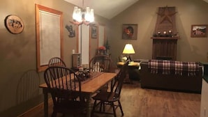 Un coin repas chaleureux avec une table et des chaises en bois, un lustre et une cheminée.