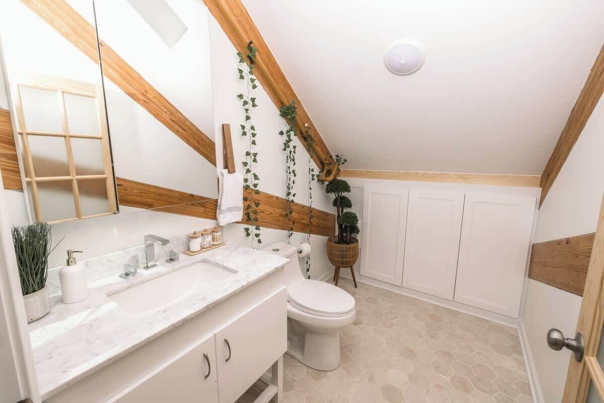 A modern bathroom with a white vanity, a toilet, and a shower area.