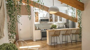 Eine moderne Küche mit Holzbalken, weißen Schränken und einer Bar mit Barhocker.