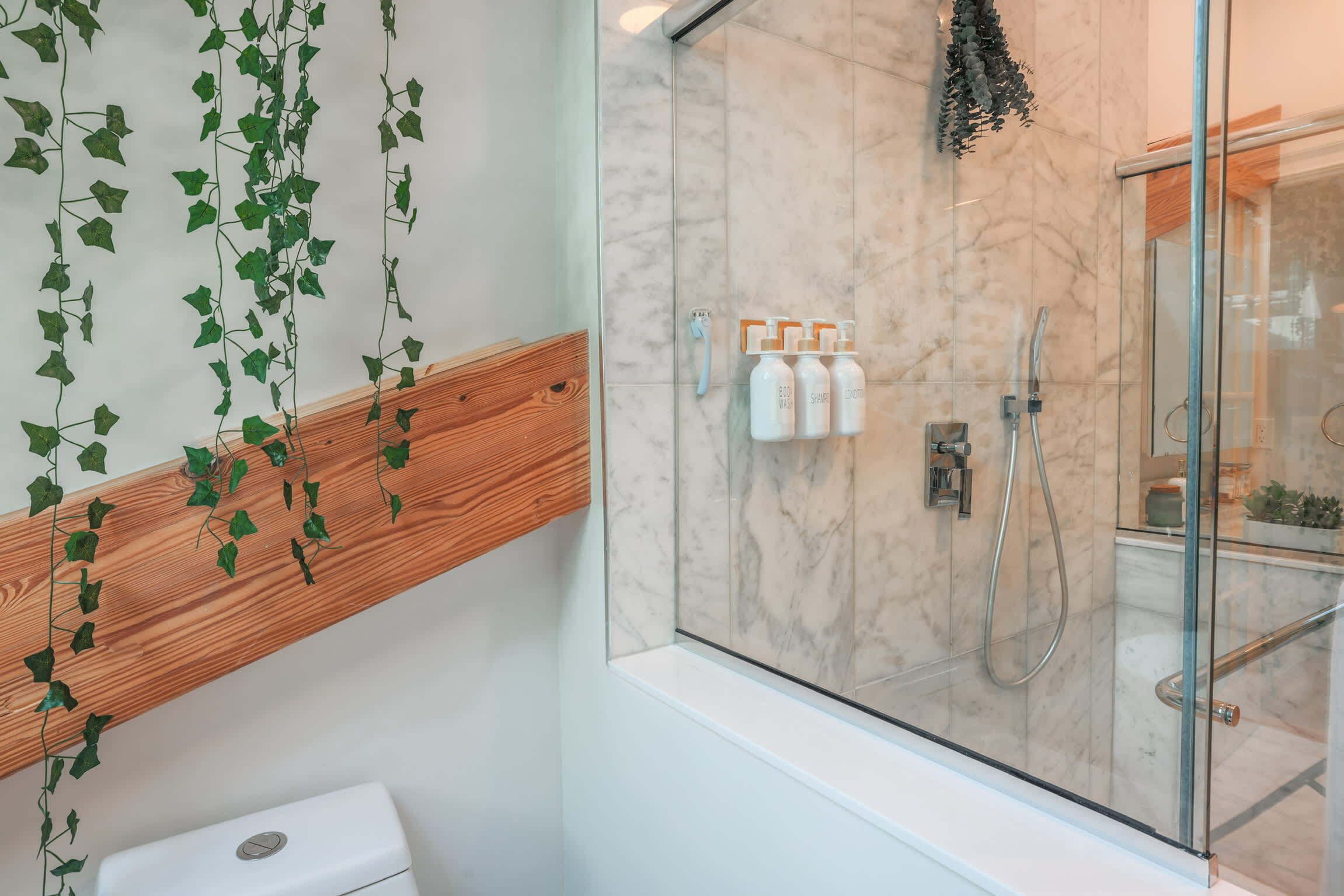 Un baño moderno con cabina de ducha de vidrio, tocador de madera y un inodoro.