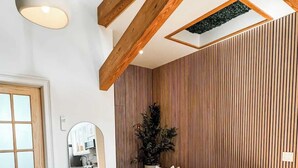 Ein modernes Wohnzimmer mit Holzboden, einer Couch, einem runden Couchtisch und einem gemusterten Teppich.