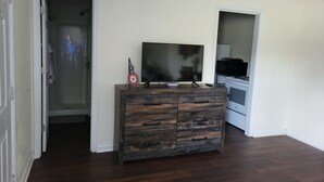 Een kamer met een donkere houten dressoir, een flatscreen televisie erop en een witte oven op de achtergrond.