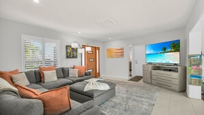 Ein modernes Wohnzimmer mit einem grauen Ecksofa, einem Flachbildfernseher und einer Holzkabine.