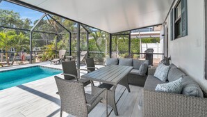 Eine Außenpatio mit Pool, Korbmöbeln und Blick auf die umliegende Vegetation.