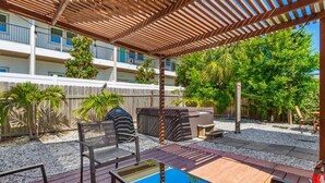 Ein überdachter Außenbereich mit Billardtisch, Sitzgelegenheiten und einer Holz-Pergola.