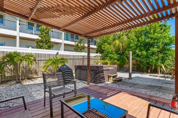 A covered outdoor area with a pool table, seating, and a wooden pergola.